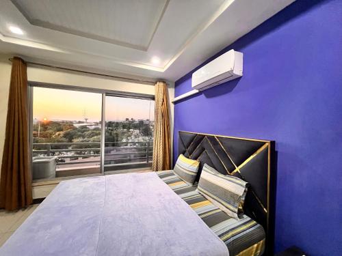 a purple bedroom with a bed and a large window at Comfortable Apartment Bahria town Rawalpindi in Rawalpindi