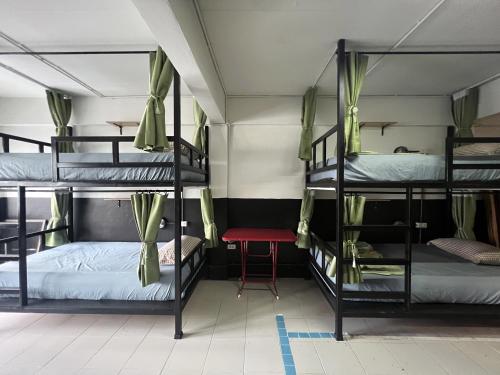 a room with three bunk beds and a red stool at Years 1981 in Bangkok
