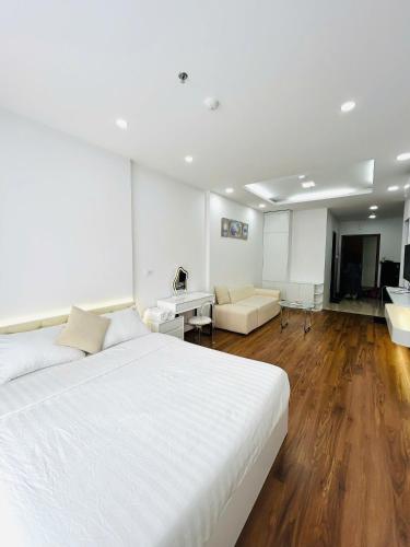 a bedroom with a large white bed and a living room at Moon Room Green Pearl Bac Ninh in Hòa Ðình