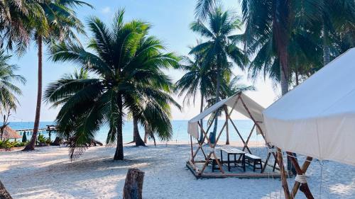 a tent and chairs on a beach with palm trees at Sunshine Resort Hotel Coconut Beach Koh Rong in Phumĭ Kaôh Rŏng
