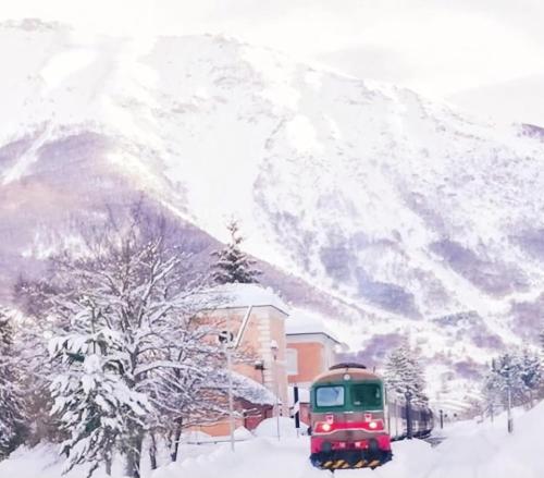 a red train traveling down a snow covered mountain at Villa MARGHERITA in Pratola Peligna