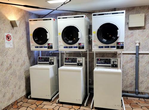 four washers and dryers are lined up against a wall at ロッジＴＯＮＢＯ・石打 in Minami Uonuma