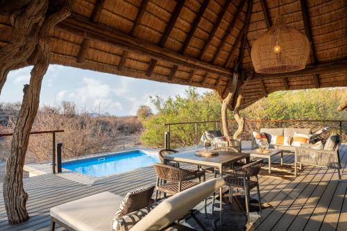 a patio with a table and chairs and a pool at Tuningi Safari Lodge in Madikwe Game Reserve