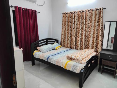 a bedroom with a bed and curtains and a table at Sole shell Chalets in Kappil