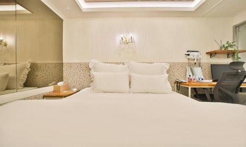 a bedroom with a large white bed and a desk at Daegu February Hotel DongdaeguStation in Daegu