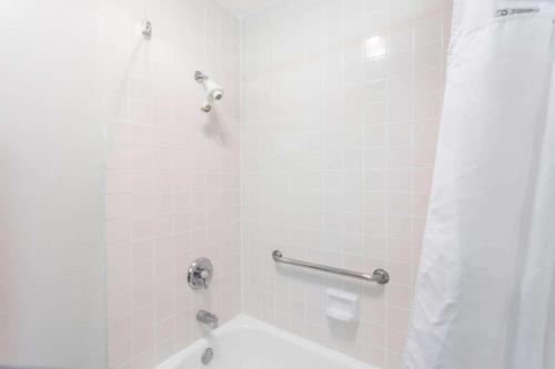 a bathroom with a shower with a white tub at Ramada by Wyndham Oceanside in Oceanside