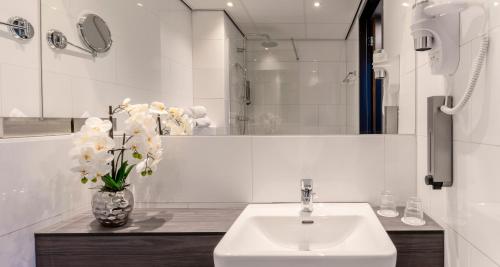 a bathroom with a sink and a vase of flowers at PLAZA Premium Almere in Almere