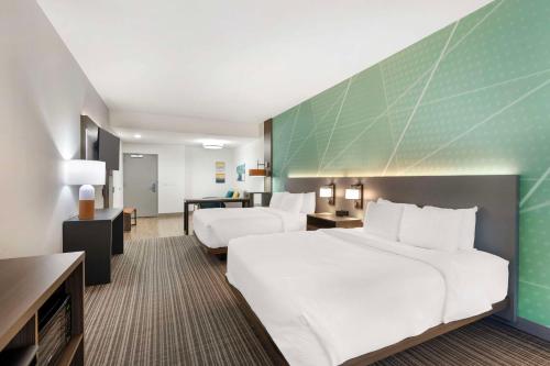 a hotel room with two beds and a green wall at Comfort Suites Titusville near Kennedy Space Center in Titusville