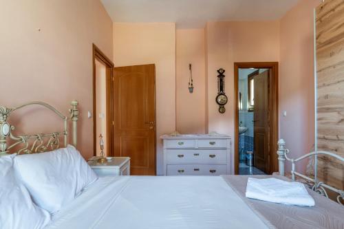 a bedroom with a white bed and a dresser at Moraki Apartment 2 Andros in Korthi