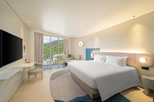 a hotel room with a bed and a television at Centara Karon Resort Phuket in Karon Beach