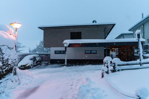a house covered in snow in front of a house at Mid Mountain Apartment Tirol in Wiesing