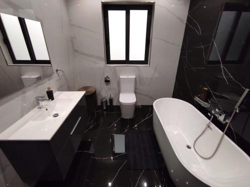 a black and white bathroom with a tub and a sink at Flat 1, spacious 3 bedroom near Beaches and Countryside in Mġarr