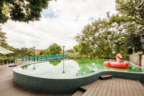 桂林市にあるGuilin Red Roof Garden Resort --Within 8000 square meter lush garden- Fluent English-Southeast Asian style decoration-Quiet and delightfulの水中のピンクの白鳥が泳ぐスイミングプール