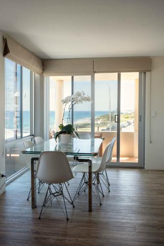 a dining room with a glass table and chairs at Cottesloe Beach View Apartments No.8 in Perth