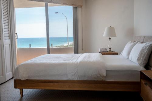a bedroom with a bed with a view of the ocean at Cottesloe Beach View Apartments No.8 in Perth