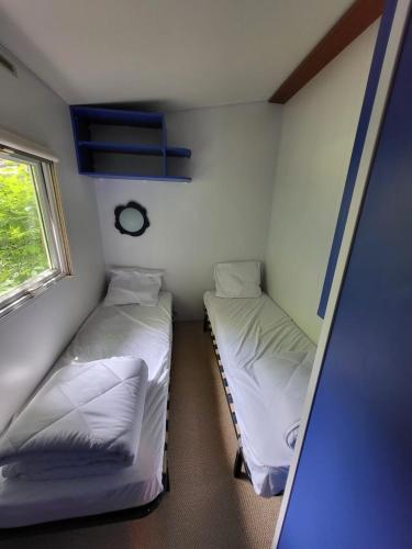 deux lits dans une petite pièce avec une fenêtre dans l'établissement L évasion, à Saint-Thomas-en-Royans