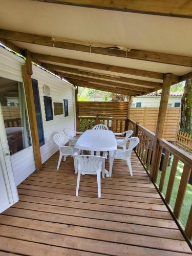 une table et des chaises blanches sur une terrasse en bois dans l'établissement L évasion, à Saint-Thomas-en-Royans