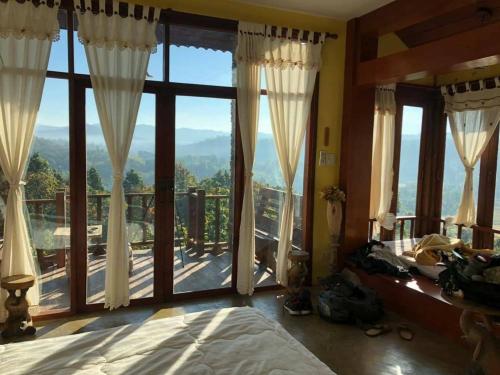 a bedroom with a large window with a view at Khunyuam Resort in Ban Khun Yuam