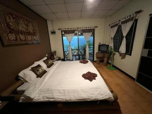 a bedroom with a large white bed with a window at Khunyuam Resort in Ban Khun Yuam