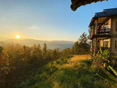 a house on a hill with the sunset in the background at Khunyuam Resort in Ban Khun Yuam