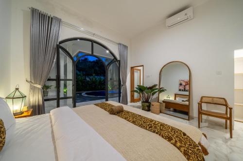 a bedroom with a large bed and a large window at Omm - Luxury Awaits - Brand New 3-Bedroom Villa with Huge Pool in a Perfect Spot in Canggu