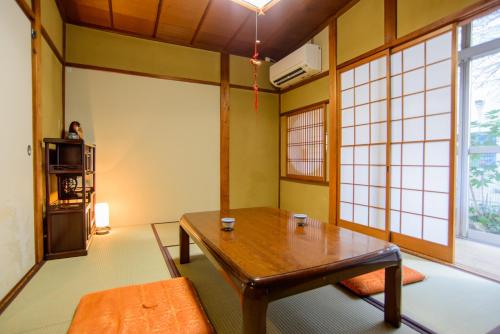 ein Wohnzimmer mit einem Holztisch und Fenstern in der Unterkunft Guesthouse Kyoto Kaikonoyashiro in Kyoto