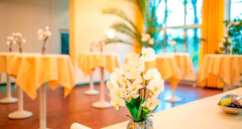 a vase filled with white flowers sitting on a table at PLAZA INN Chemnitz in Chemnitz