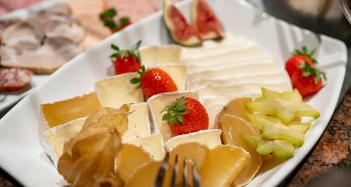 a plate of cheese and fruit on a table at PLAZA INN Chemnitz in Chemnitz