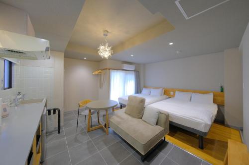 a room with a bed and a table and a kitchen at Grand Pia 2, Bentencho in Osaka