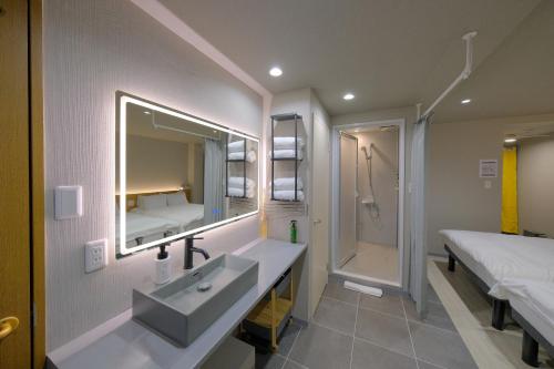 a bathroom with a sink and a bed and a mirror at Grand Pia 2, Bentencho in Osaka