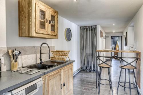 une cuisine avec un évier et un comptoir avec des tabourets dans l'établissement Appartement Chez Albert situé 25KM Chamonix, à Saint-Gervais-les-Bains