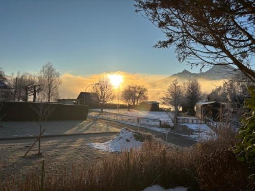a snowy field with the sun setting in the background at Seehaus Herzog in Drobollach am Faakersee