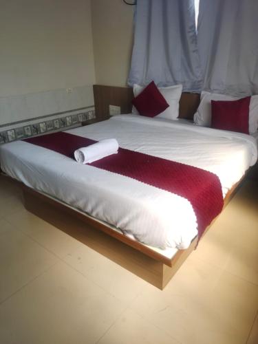 a large bed with a red and white blanket on it at Sun Bright Residency Badlapur in Badlapur