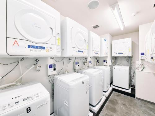 a laundry room with white washers and dryers at Kyoto Guesthouse HIVE in Kyoto