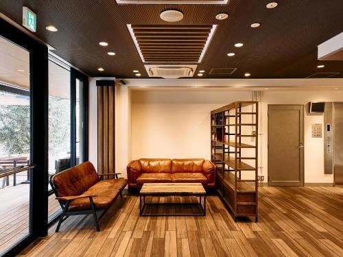 a waiting room with a leather couch and a book shelf at Kyoto Guesthouse HIVE in Kyoto