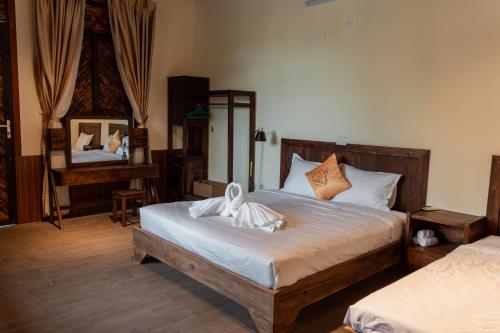 a bedroom with a large bed and a mirror at D Banlieue Homestay And Coffee TP Kon Tum in Kon Tum