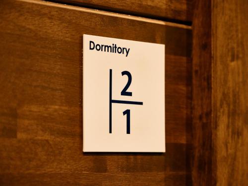 a white sign on a wooden door with the number at Kyoto Guesthouse HIVE in Kyoto