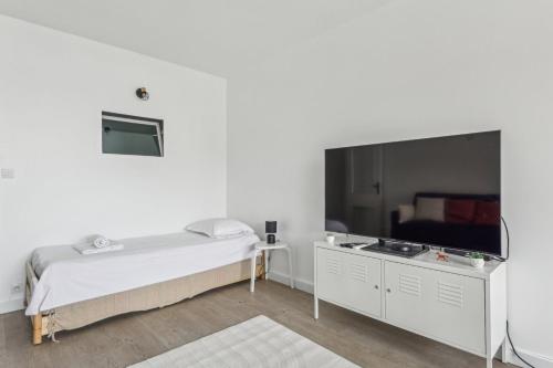 - une chambre avec un lit et une grande télévision à écran plat dans l'établissement Le Familial - Charming apartment in Paris, à Paris