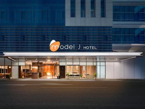 a hotel with a sign on the front of a building at Model J Hotel Jakarta Soekarno - Hatta Airport 曼居酒店 雅加达苏加诺哈达机场店 in Gardu
