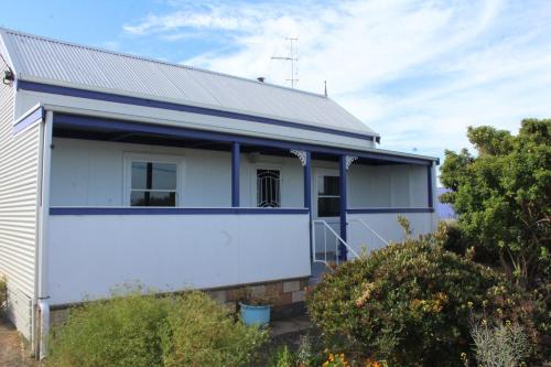 a white house with blue accents on it at Cosy 3 bedroom cottage in the centre of Kingscote in Kingscote