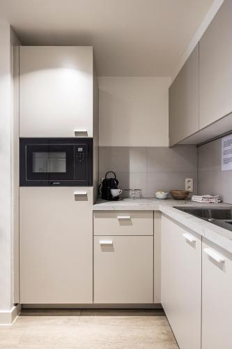 a kitchen with white cabinets and a microwave at House 22 longstay in Kortrijk