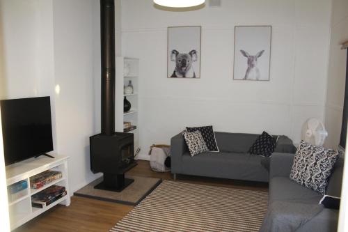 a living room with a couch and a flat screen tv at Cosy 3 bedroom cottage in the centre of Kingscote in Kingscote