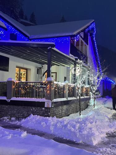 a house decorated with christmas lights in the snow at Vila Casa cu Tei in Lupeni