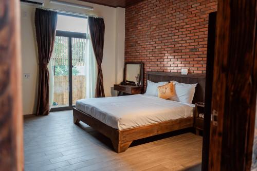 a bedroom with a bed and a brick wall at D Banlieue Homestay And Coffee TP Kon Tum in Kon Tum