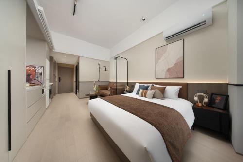 南京Nanjing Olympic Sports Center Suisse Place Apartment Hotel的卧室里有一张白色的大床和一张沙发