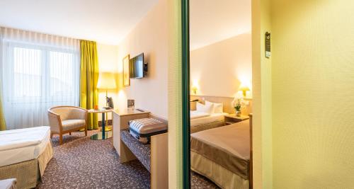 a hotel room with two beds and a desk at PLAZA INN Chemnitz in Chemnitz