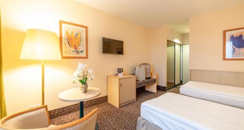 a hotel room with a bed and a table with flowers at PLAZA INN Chemnitz in Chemnitz