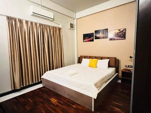 a bedroom with a bed with white sheets and yellow pillows at Vientiane Star Hotel B in Vientiane