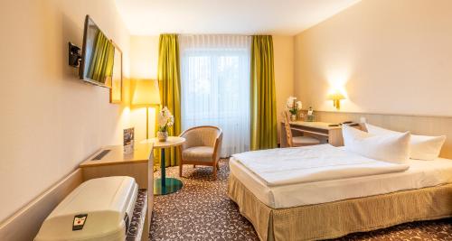 a hotel room with a bed and a desk at PLAZA INN Chemnitz in Chemnitz