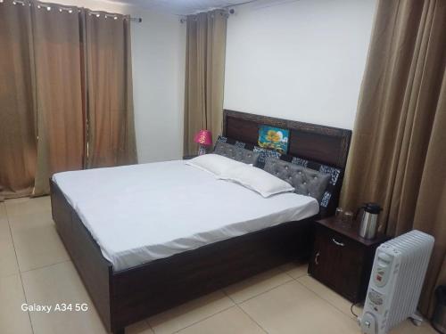 a bedroom with a large bed with white sheets and a night stand at InnBox Farmstay - Rajpura Punjab in Banūr